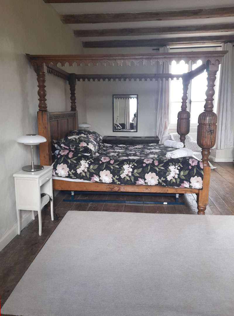 beautiful four poster bed with floral bedding in large overnight accommodation