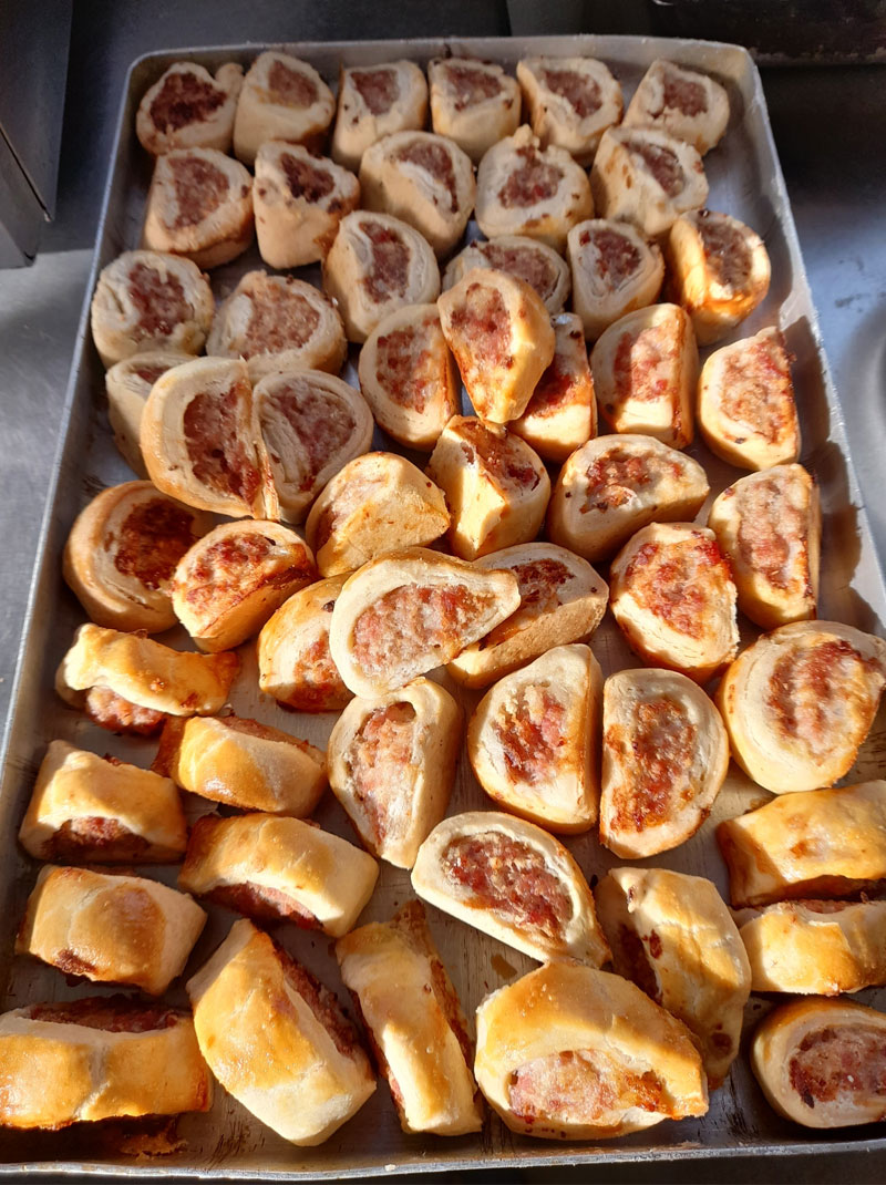 lots of home made sausage rolls on a big square tray